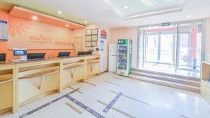 A reception area with a counter, computers, a vending machine, and a glass door leading outside. - Ginza Jiayi Hotel (Yantai Suocheng Wanda Plaza Branch) (Yantai)