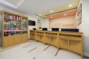 A reception area with a counter, a display cabinet with items, and a wall with text. - Ginza Jiayi Hotel (Yantai Suocheng Wanda Plaza Branch) (Yantai)