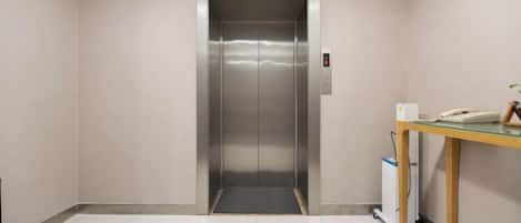 An elevator in a hallway with a small table and a phone on it.