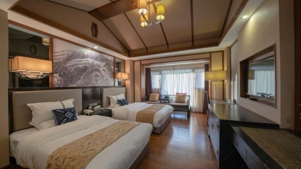 Une chambre d’hôtel avec deux lits, un grand tableau, un bureau et une chaise.