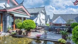 Une cour traditionnelle agrémentée de plantes en pot, d’un petit élément décoratif aquatique et de sièges d’extérieur.