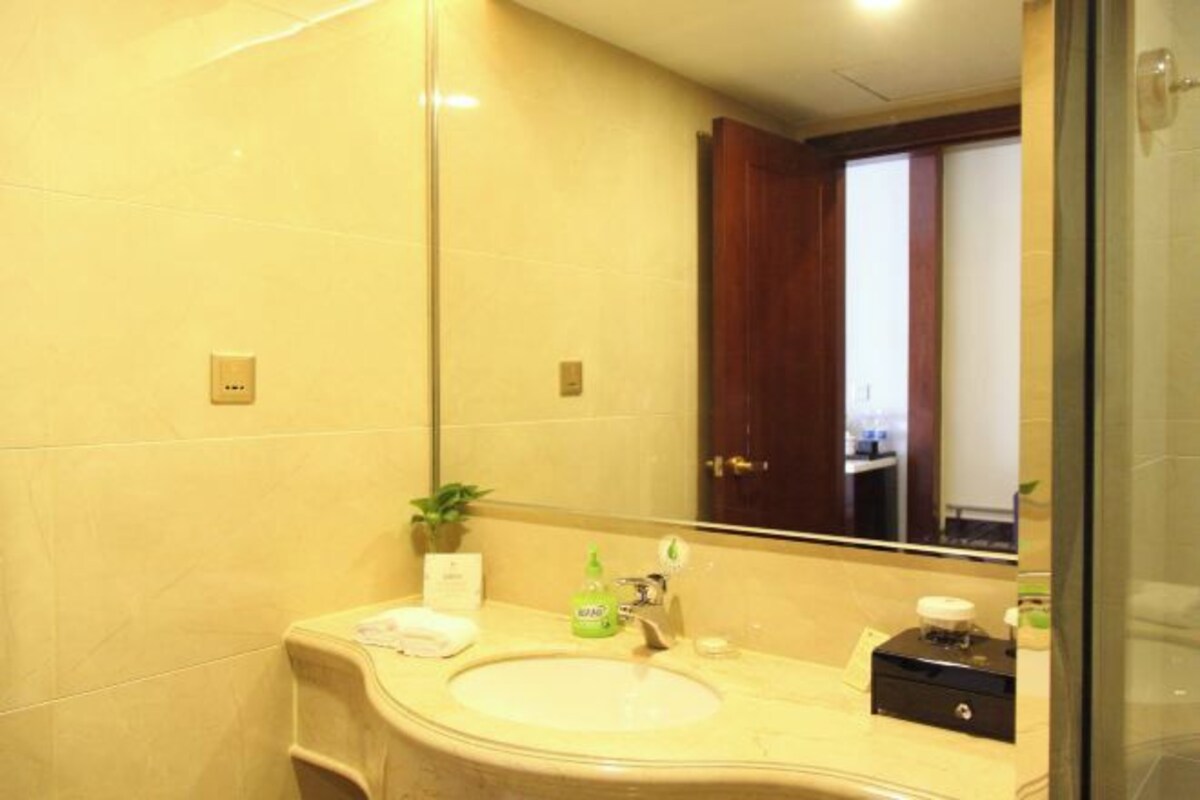A bathroom with a large mirror, a sink, and a vanity with toiletries.