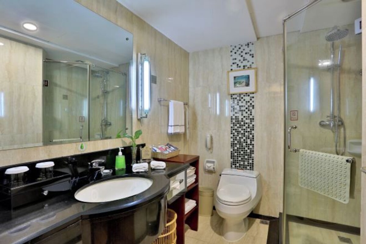 A modern bathroom with a large mirror, dual sinks, a toilet, and a glass-enclosed shower.