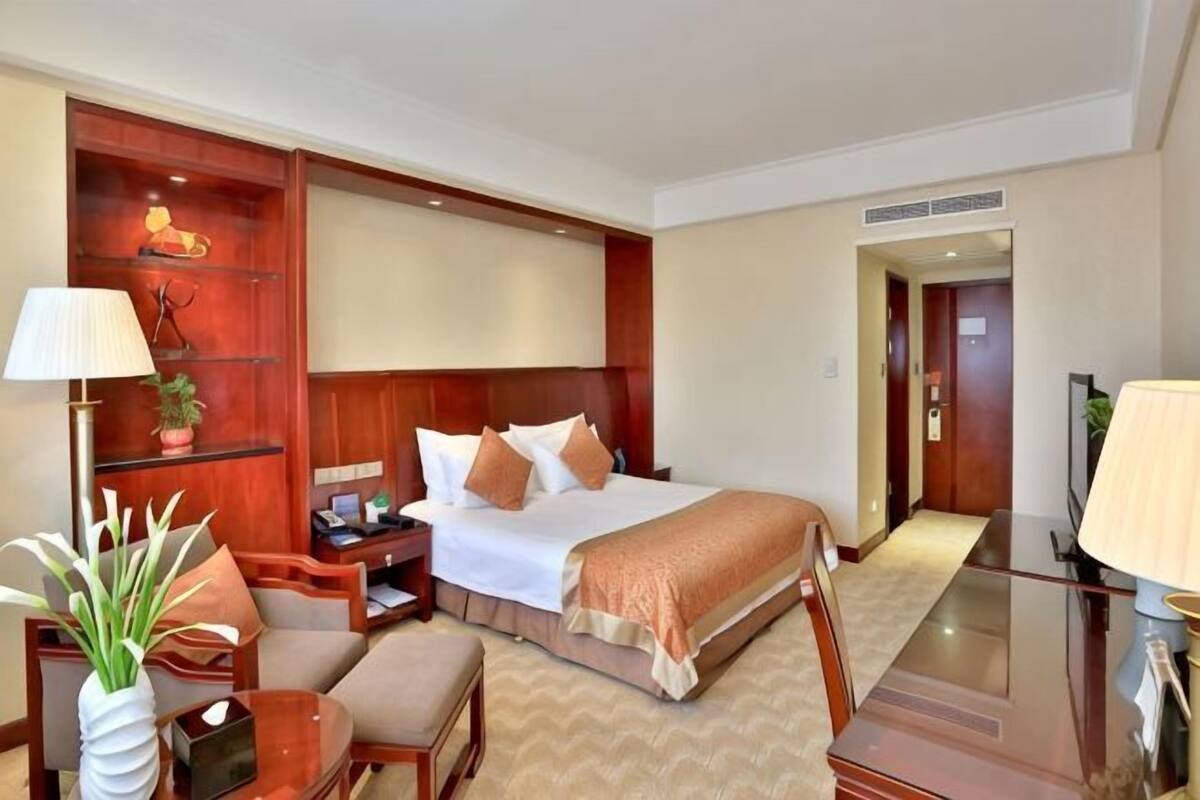 Ein Hotelzimmer mit Bett, Nachttisch, Lampe, Stuhl und kleinem Tisch.