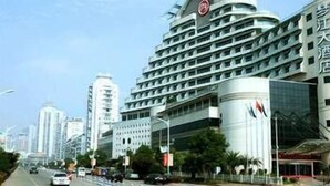 A modern hotel with a distinctive curved facade, multiple balconies, and a prominent logo on the top. - Mengjiang Hotel (Wenzhou)