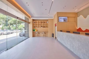 A modern reception area with a glass partition, a reception desk, and a seating area with stools. - ELONG R YUNHotel (Ningbo Yonggang North Road) (NINGBO)