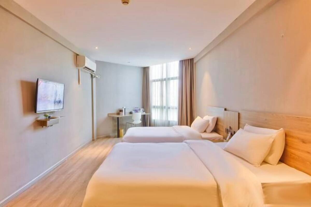 Une chambre d’hôtel avec deux lits, une télévision, un bureau et une fenêtre.