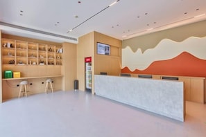 A reception area with a counter, seating, and a display of items on shelves. - ELONG R YUNHotel (Ningbo Yonggang North Road) (NINGBO)
