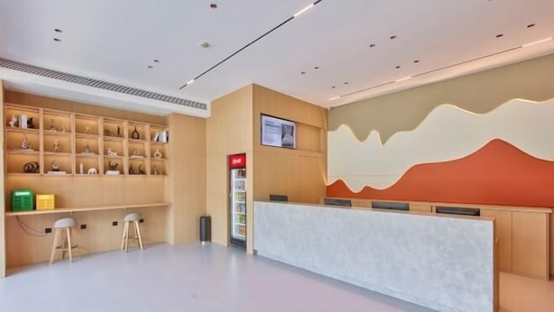 A reception area with a marble counter, wooden shelves with decorative items, and a unique wavy wall design. - ELONG R YUNHotel (Ningbo Yonggang North Road) (NINGBO)