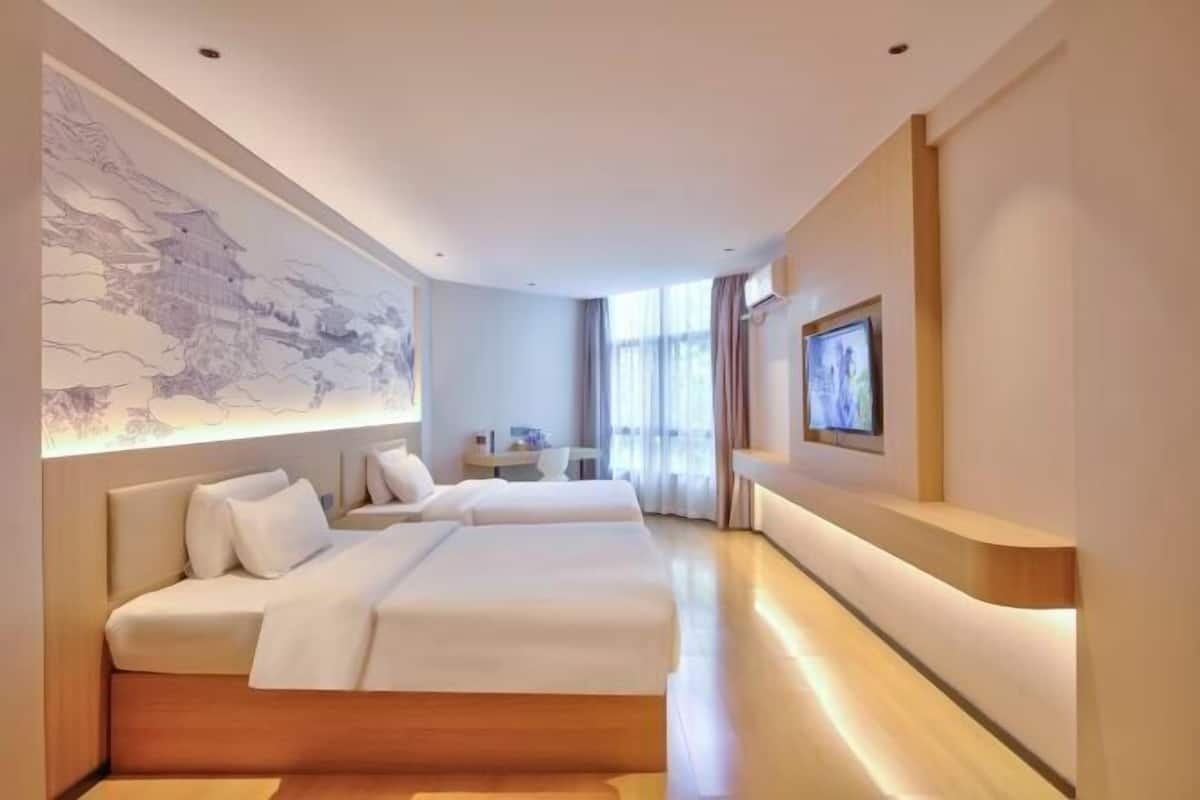 Une chambre d’hôtel avec un grand lit, un bureau, une chaise, une télévision et un mur orné d’une carte.