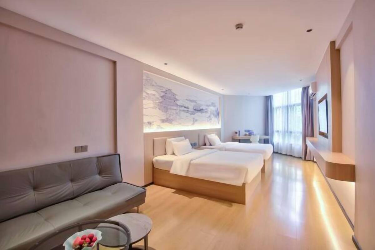 Une chambre d’hôtel moderne équipée d’un canapé, d’un lit, d’un bureau et d’une grande œuvre d’art accrochée au mur.