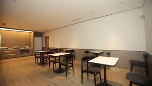 A conference room with tables and chairs, a projection screen, and a podium.