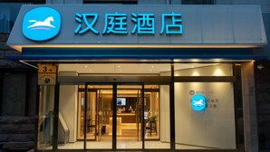 A hotel entrance with a sign indicating '汉庭酒店' and a reception desk visible inside.