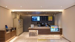 A hotel reception area with a digital display, a coffee machine, and a beverage cooler.