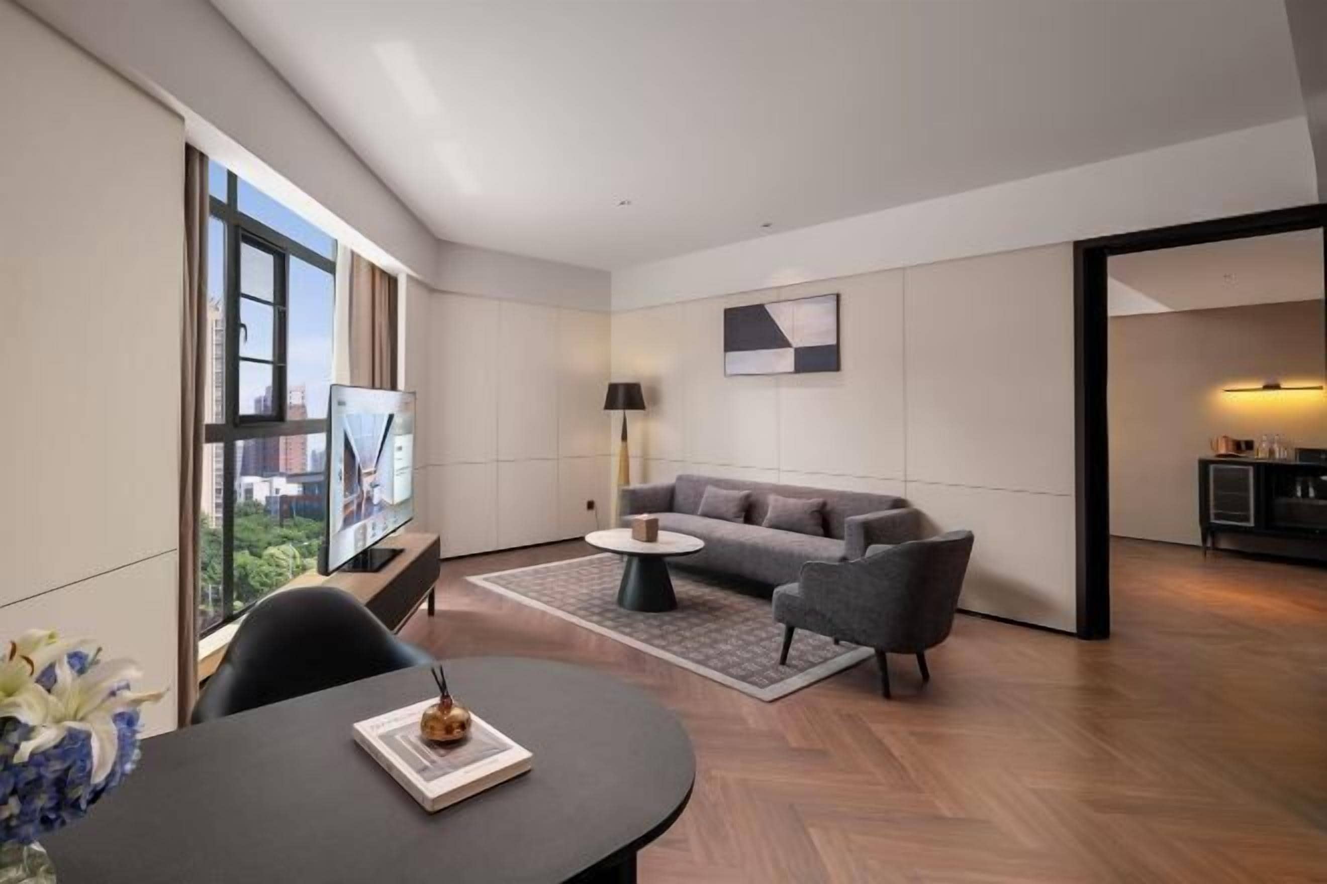 A modern living room with a sofa, coffee table, and a dining area with a table and chairs.