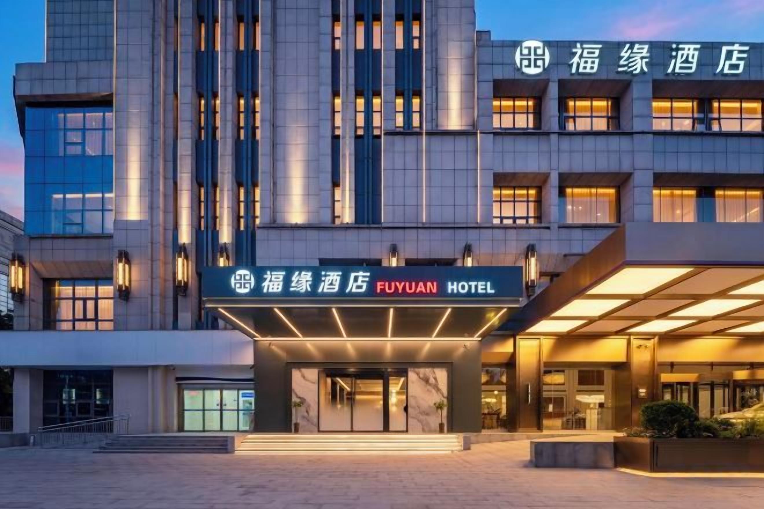 A hotel entrance with a modern facade, a prominent signage, and a well-lit entrance area.