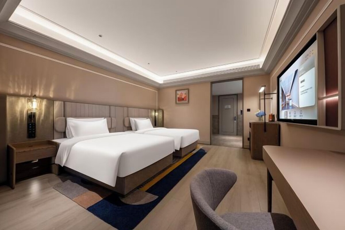Una camera d'albergo con un letto grande, comodini, una scrivania e un televisore.