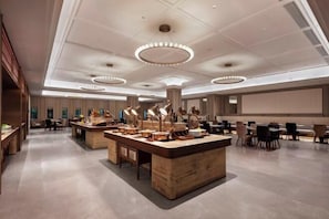 Een moderne hotelentree met een centraal receptiegedeelte, verschillende zithoeken en een groot scherm voor presentaties.