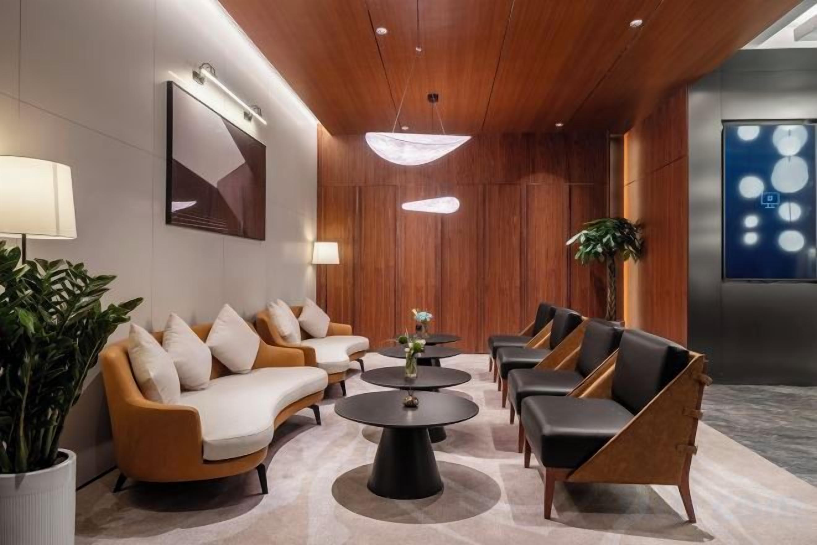 A modern lobby with a sofa set, coffee tables, and a large plant.