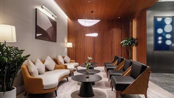 A modern lobby with a sofa set, coffee tables, and a large plant.