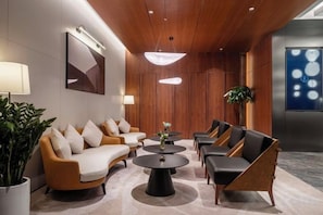 A modern lobby with a sofa set, coffee tables, and a large plant. - Fuyuan Hotel (Zhengzhou East Station Provincial Government Branch) (Zhengzhou)