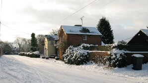 A snow-covered rural road with houses on either side. - The Compasses Inn (Chelmsford)