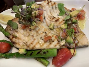 A plate of grilled fish with vegetables and a lemon wedge. - The Compasses Inn (Chelmsford)