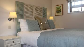 A bedroom with a bed, two bedside lamps, a nightstand, and a framed picture on the wall.