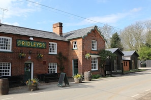 A traditional brick building with a sign reading 'RIDLEYS AND STOUT'. - The Compasses Inn (Chelmsford)