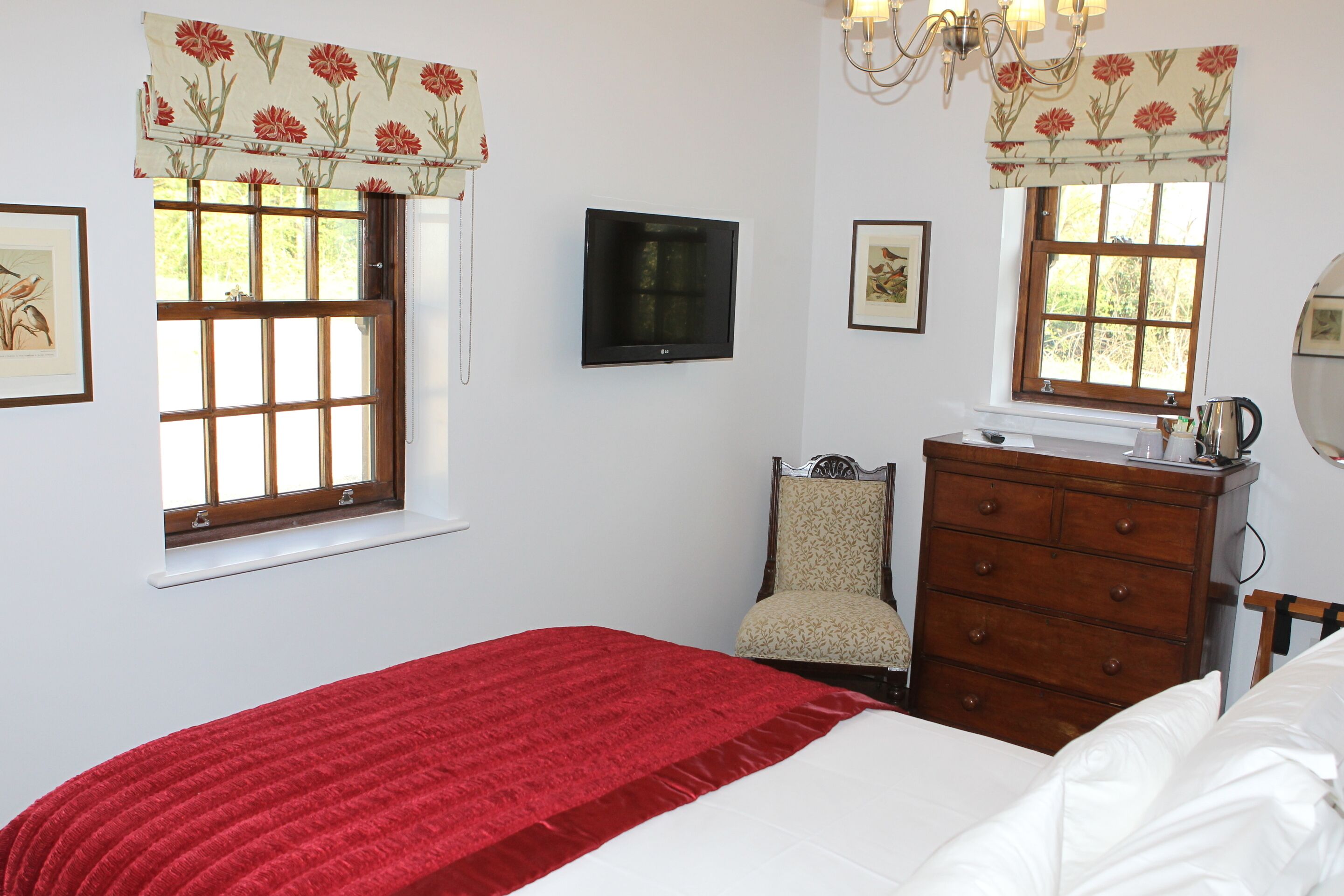 A bedroom with a bed, dresser, chair, and two windows with curtains.