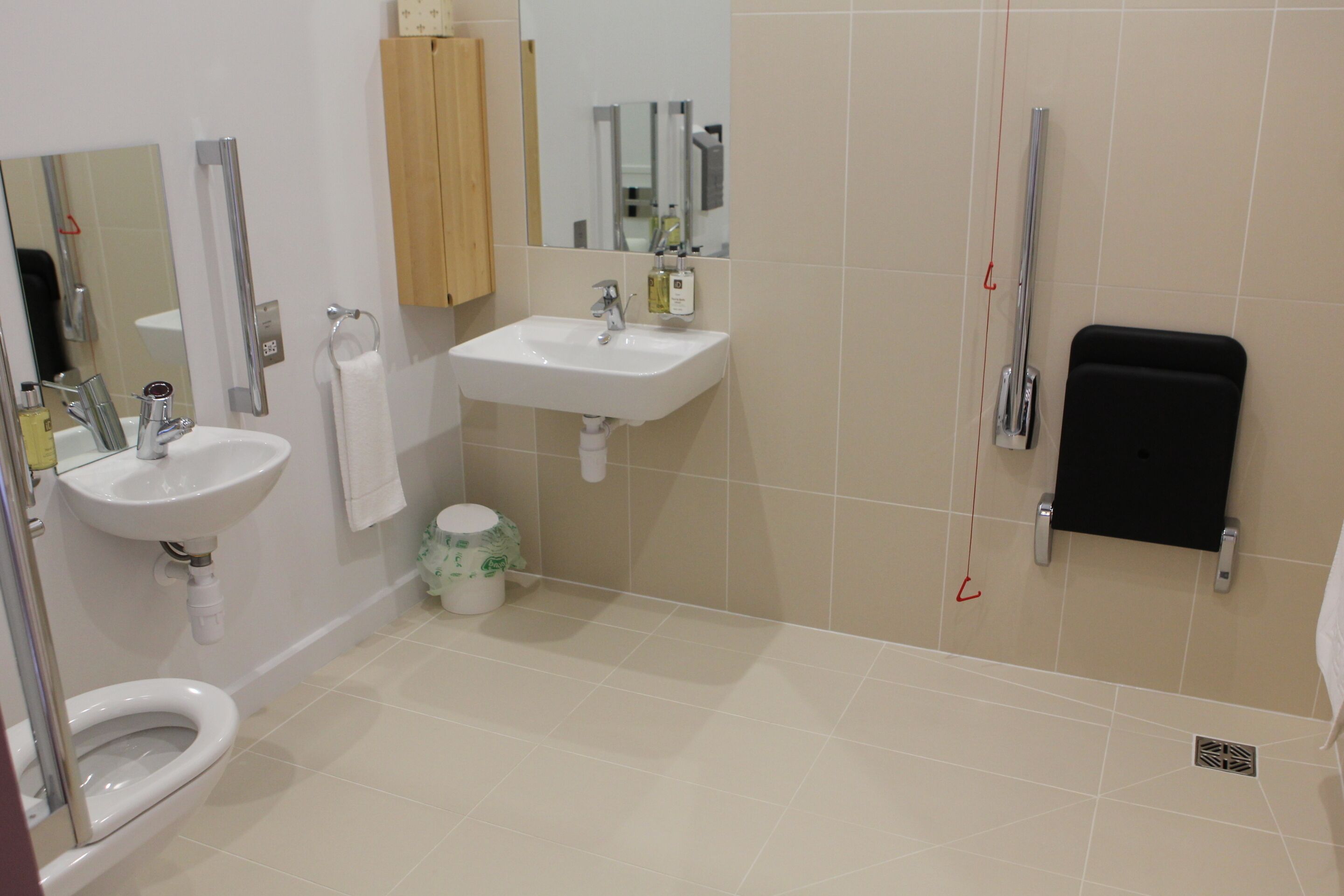 Un baño con inodoro, dos lavamanos, un espejo y zona de ducha.