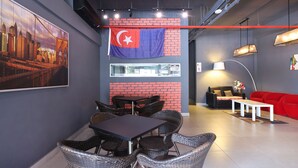 A modern interior with a dining area, a red sofa, and a flag on the wall. - Hotel O Link Inn (Johor Bahru)