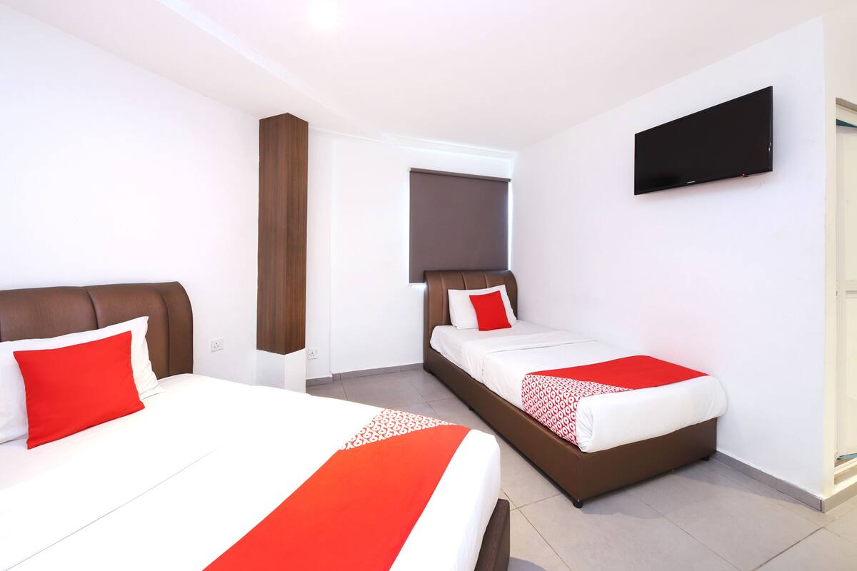 A hotel room with two beds, a TV on the wall, and a window.