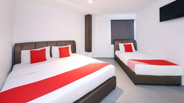 A hotel room with two beds, each with a red and white bedspread, a brown headboard, and a flat-screen TV mounted on the wall. - Hotel O Link Inn (Johor Bahru)