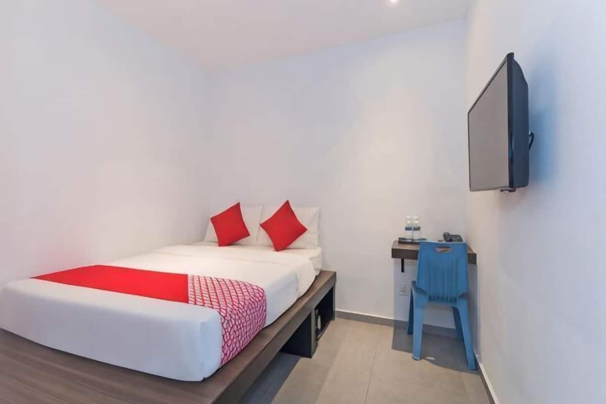 A bedroom with a bed, a desk, and a chair.