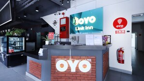 A reception desk with a 'YOYO Link Inn' sign, a fire extinguisher, and a digital clock displaying 03:00 PM. - Hotel O Link Inn (Johor Bahru)