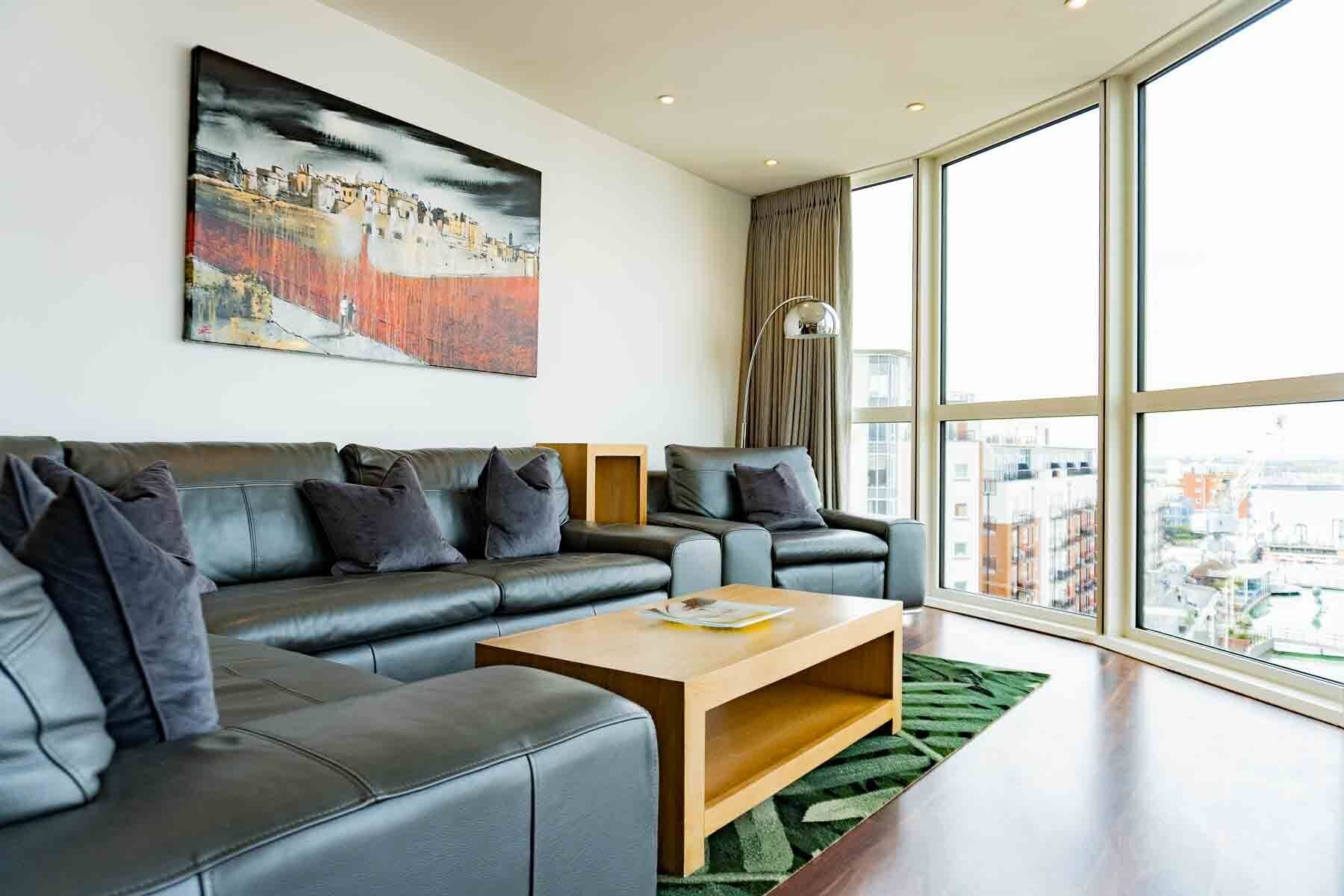 Un salon moderne avec un canapé en cuir, une table basse en bois et une grande fenêtre donnant sur la ville.
