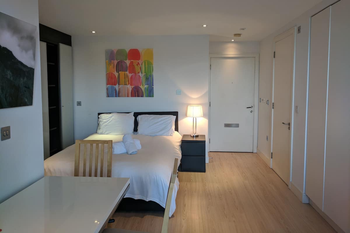Une chambre à coucher moderne avec un lit, des tables de chevet, un bureau et une armoire.