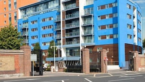 Een modern meerlaags gebouw met een blauwe gevel, grote ramen en een bakstenen basis.