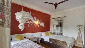 A hotel room with two beds, a ceiling fan, a decorative wall hanging, and a bedside table with water bottles. - Eden Jungle Resort (Sauraha)