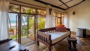 A room with a bed, a small table, and a view of the beach. - Blue Marlin Beach Hotel  (Diani Beach)