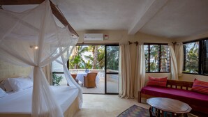 A room with a bed, a sofa, a small table, and a balcony with a table and chairs. - Blue Marlin Beach Hotel  (Diani Beach)