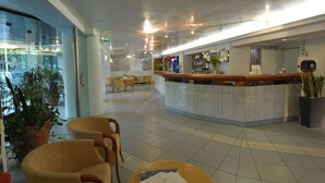 A hotel lobby with a reception desk, seating area, and potted plants. - Bellariva Feeling Hotel (Rimini)