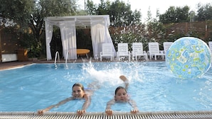 A swimming pool with two children swimming, a white gazebo, and lounge chairs. - Bellariva Feeling Hotel (Rimini)