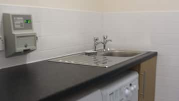 A laundry area with a washing machine and dryer, a sink, and a control panel.