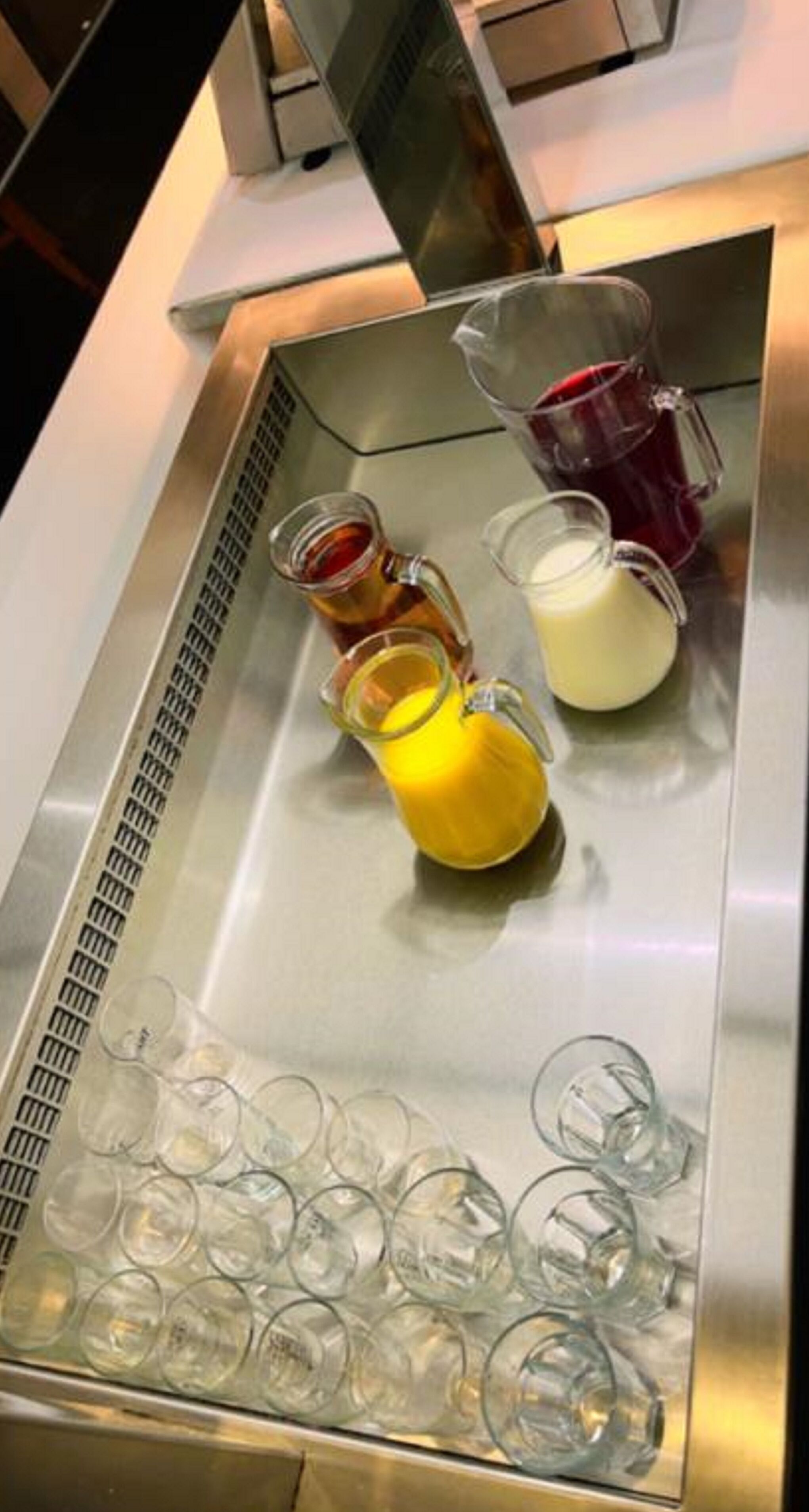 A beverage dispenser with various drinks and empty glasses.