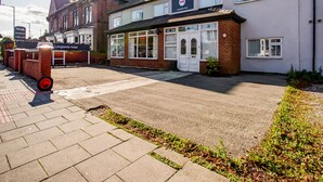 A hotel entrance with a sign for Longlands Hotel, a paved driveway, and a brick building with a white facade. - The Longlands Hotel (Middlesbrough)