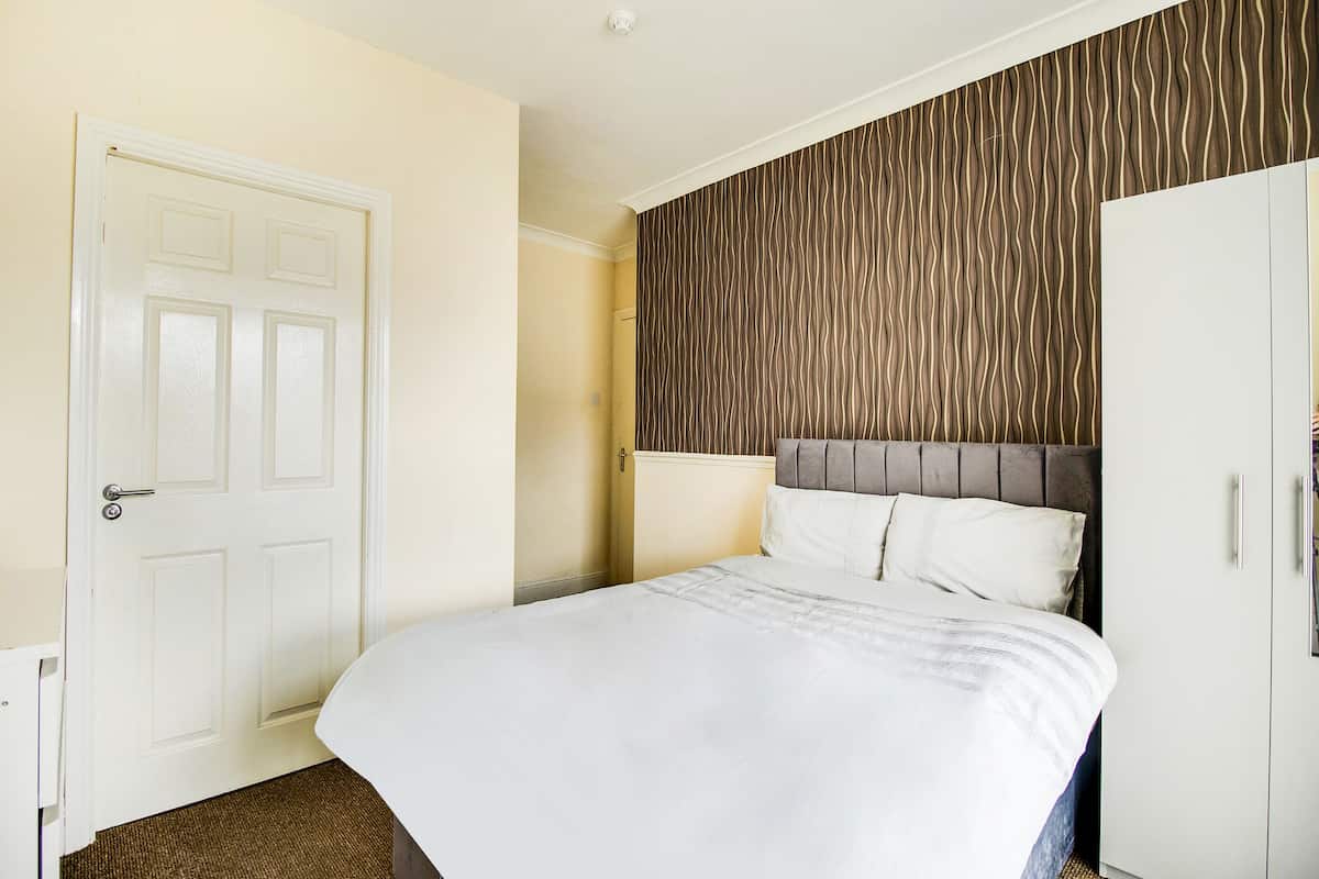 A hotel room with a bed, a wardrobe, and a door.