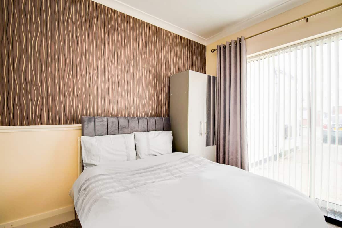 A hotel room with a bed, a wardrobe, and a window with curtains.