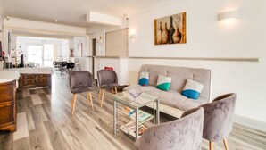A modern living room with a sofa, armchairs, and a glass coffee table. There is a dining area in the background with a table and chairs. - The Longlands Hotel (Middlesbrough)